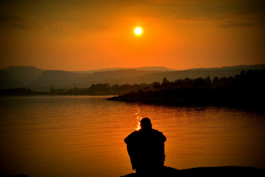 homme seul assis devant un couché de soleil